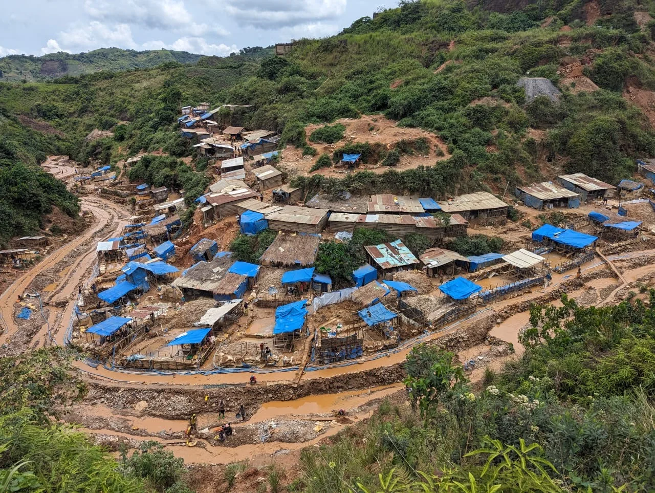 Vue aérienne d'un site minier artisanal avec des stations de lavage couvertes de bâches, à flanc de colline dans l'est de la RDC