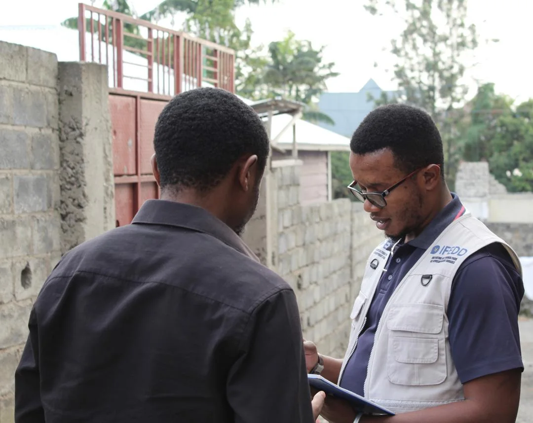 Un agent de terrain IFEDD en gilet documente un entretien lors d'une visite de suivi