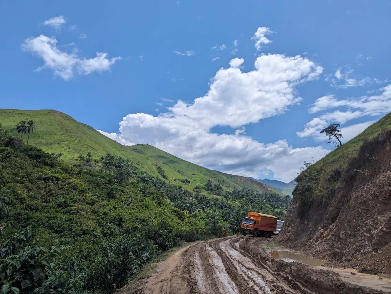Un camion sur une route boueuse de transport des minerais, entre les collines vertes de l'est de la RDC